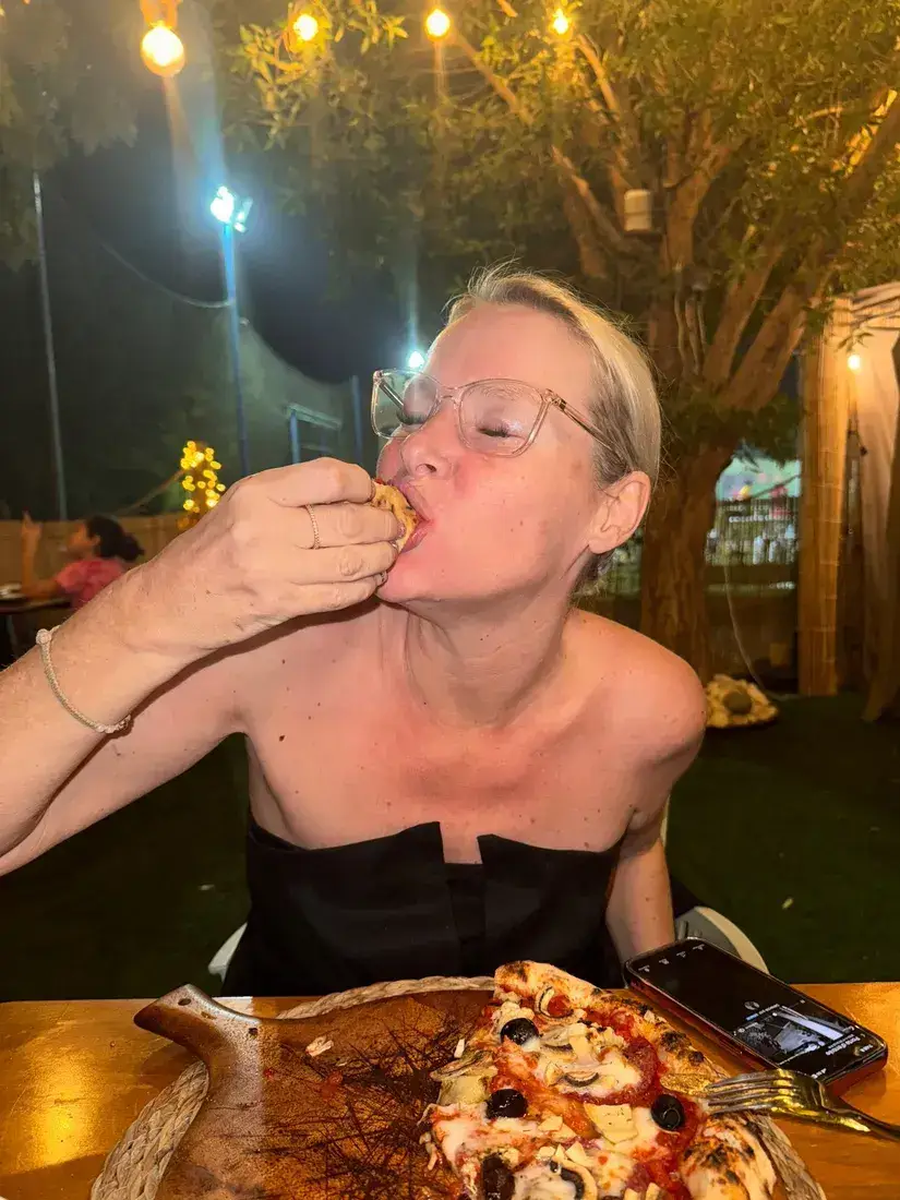 A guest taking a bite of pizza under the string lights