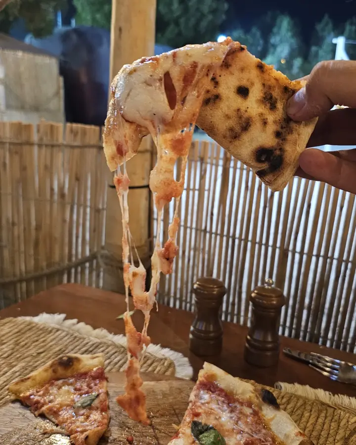 A slice of pizza lifted with stretching mozzarella